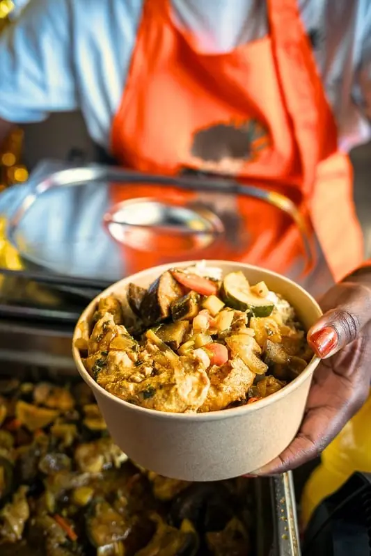 Mélissa tend un bol de cuisine créole sur son stand